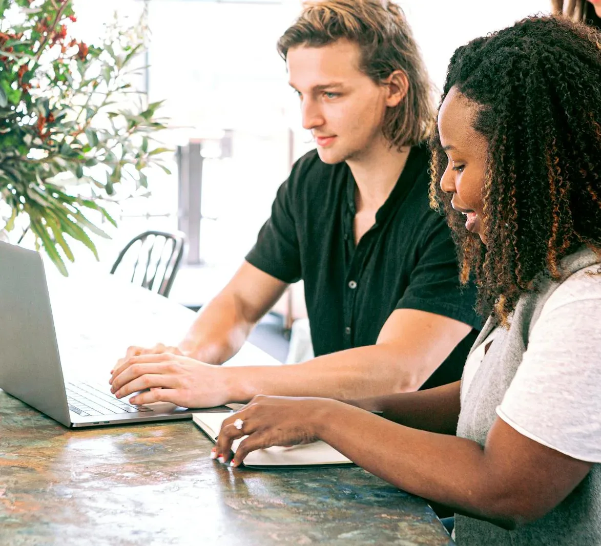 Man Working on a Laptop while Woman Takes Notes