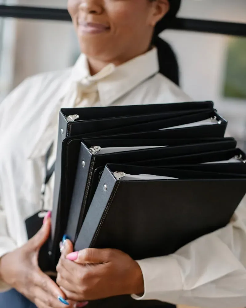 Black woman carrying pile of documents in office