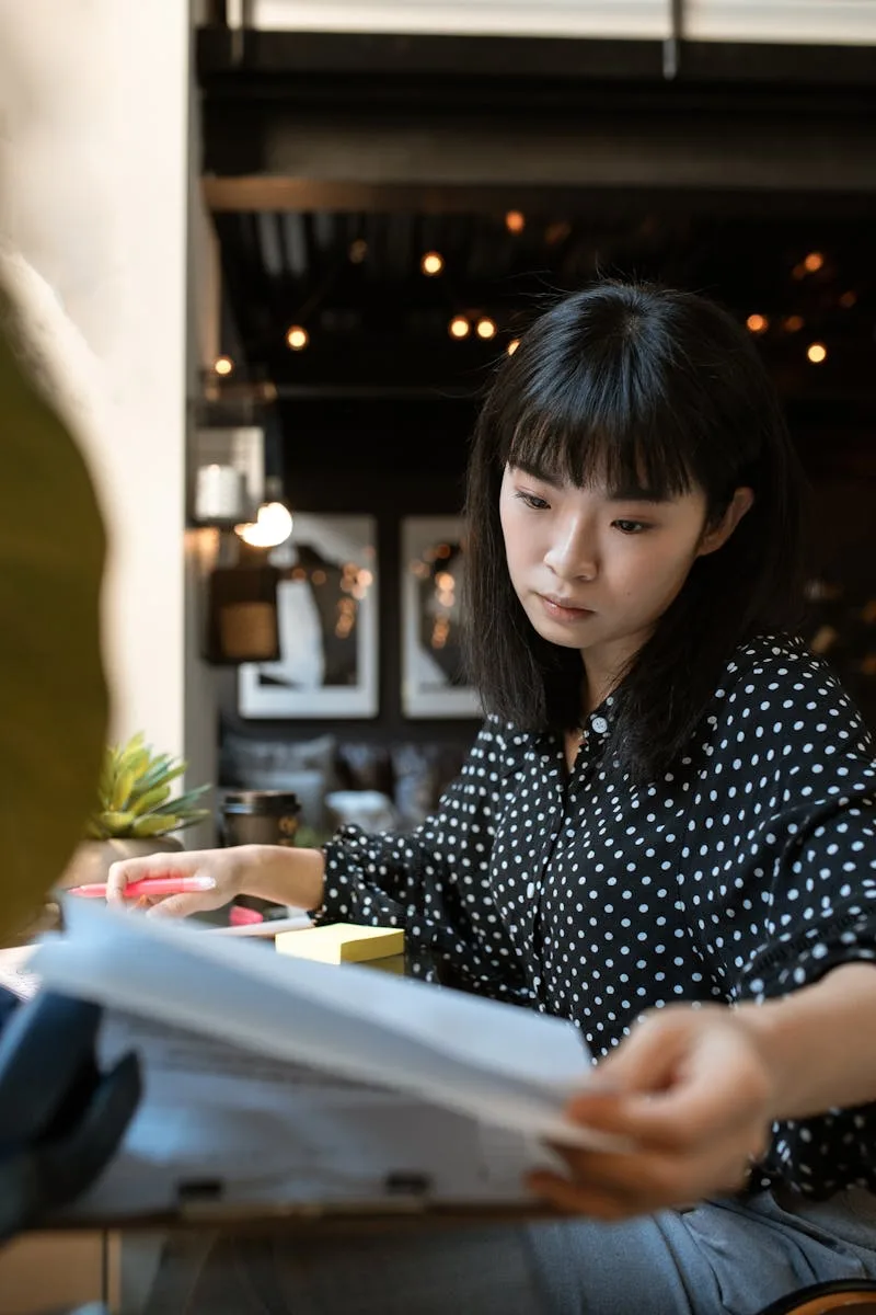 Woman in Black and White Polka Dot Shirt Sitting by the Table