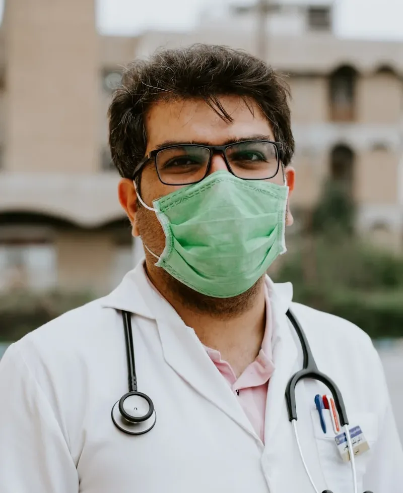 man in white scrub suit wearing green mask