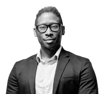 Man in suit and glasses, smiling confidently.